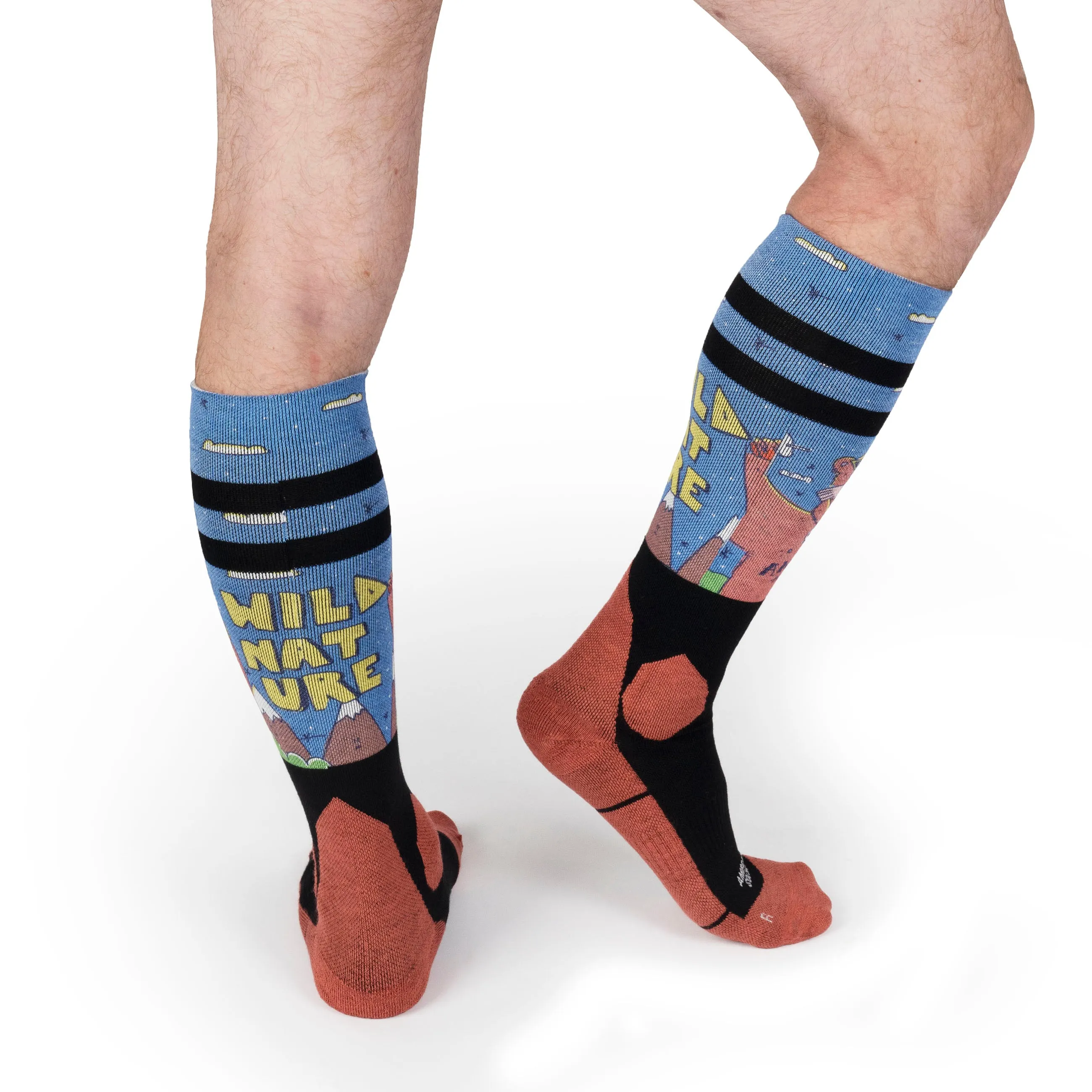 Beine mit kniehohen, hellblauen Snow Socks mit "Wild Nature"-Schriftzug, Bergen, Zeichnungen und schwarzen Streifen.
