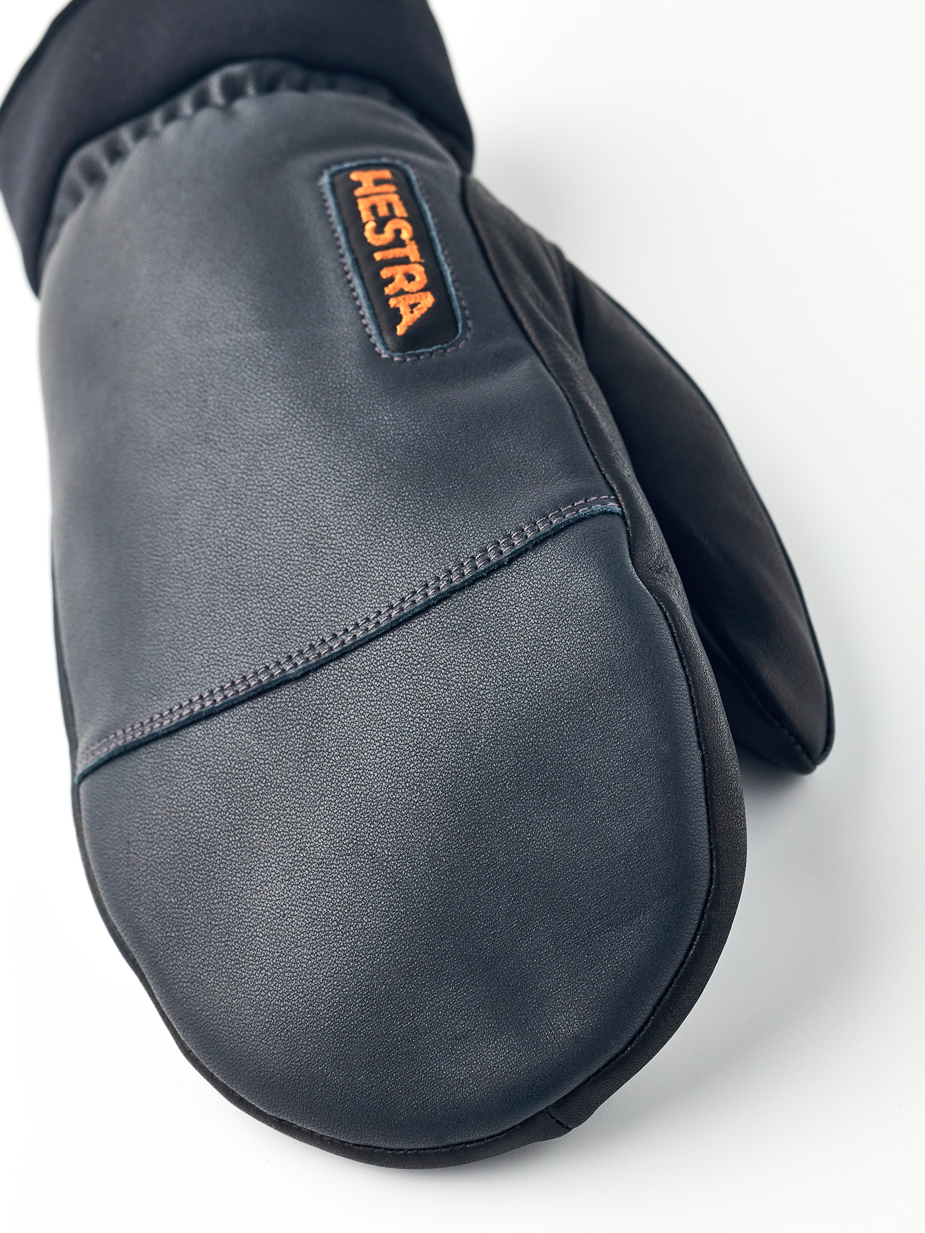 Nahaufnahme eines grauen Hestra Army Leather Wollfrottee-Fäustlings mit sichtbarem Hestra-Logo.