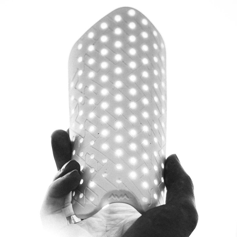 Eine Hand hält einen Flaxta Aircon Schienbeinschoner, der mit Belüftungslöchern versehen ist.