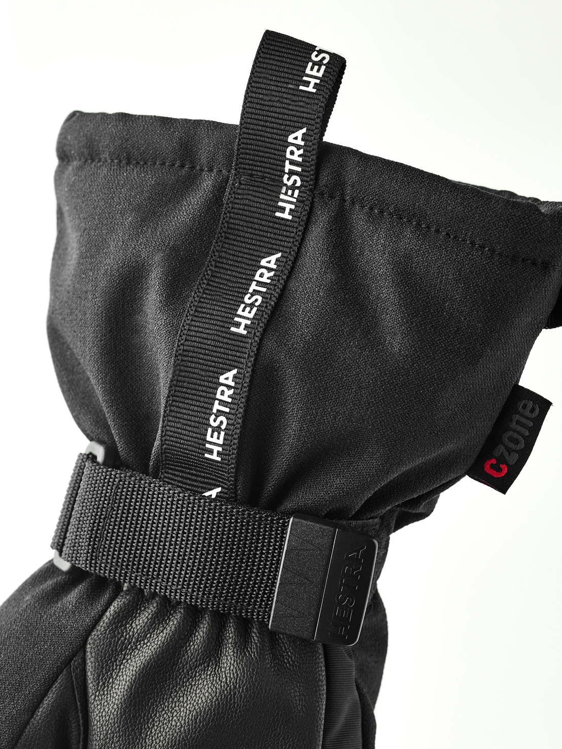 Hestra Handschuh Schwarz Nahaufnahme eines schwarzen Hestra-Handschuhs mit Stoffschlaufe und Handgelenksband. Das CZone-Logo ist sichtbar.