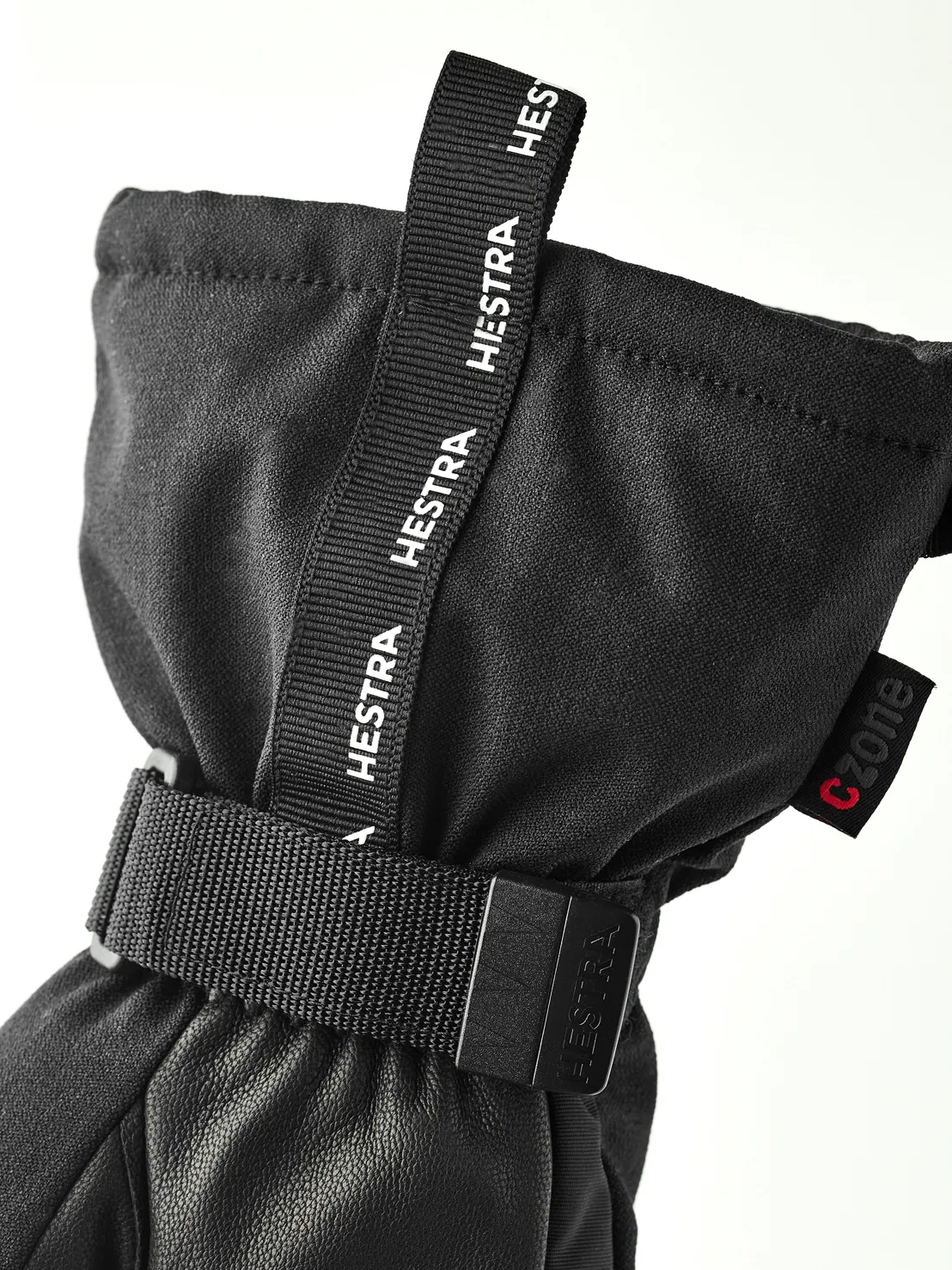 Nahaufnahme eines schwarzen Hestra-Handschuhs mit Stoffschlaufe und Handgelenksband. Das CZone-Logo ist sichtbar.