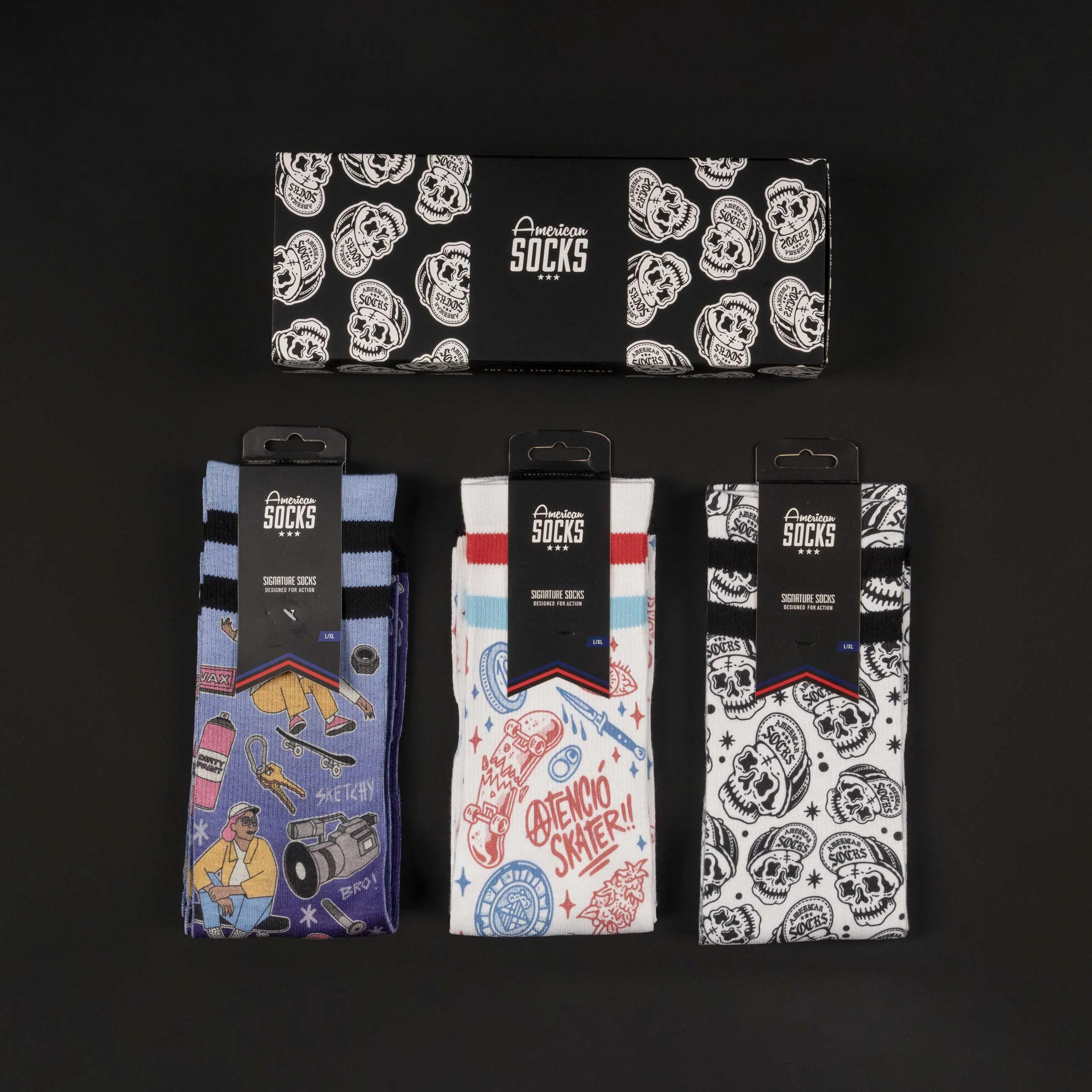 Drei Paar American Skater Socks mit Motiv, verpackt in Geschenkbox, auf schwarzem Grund.