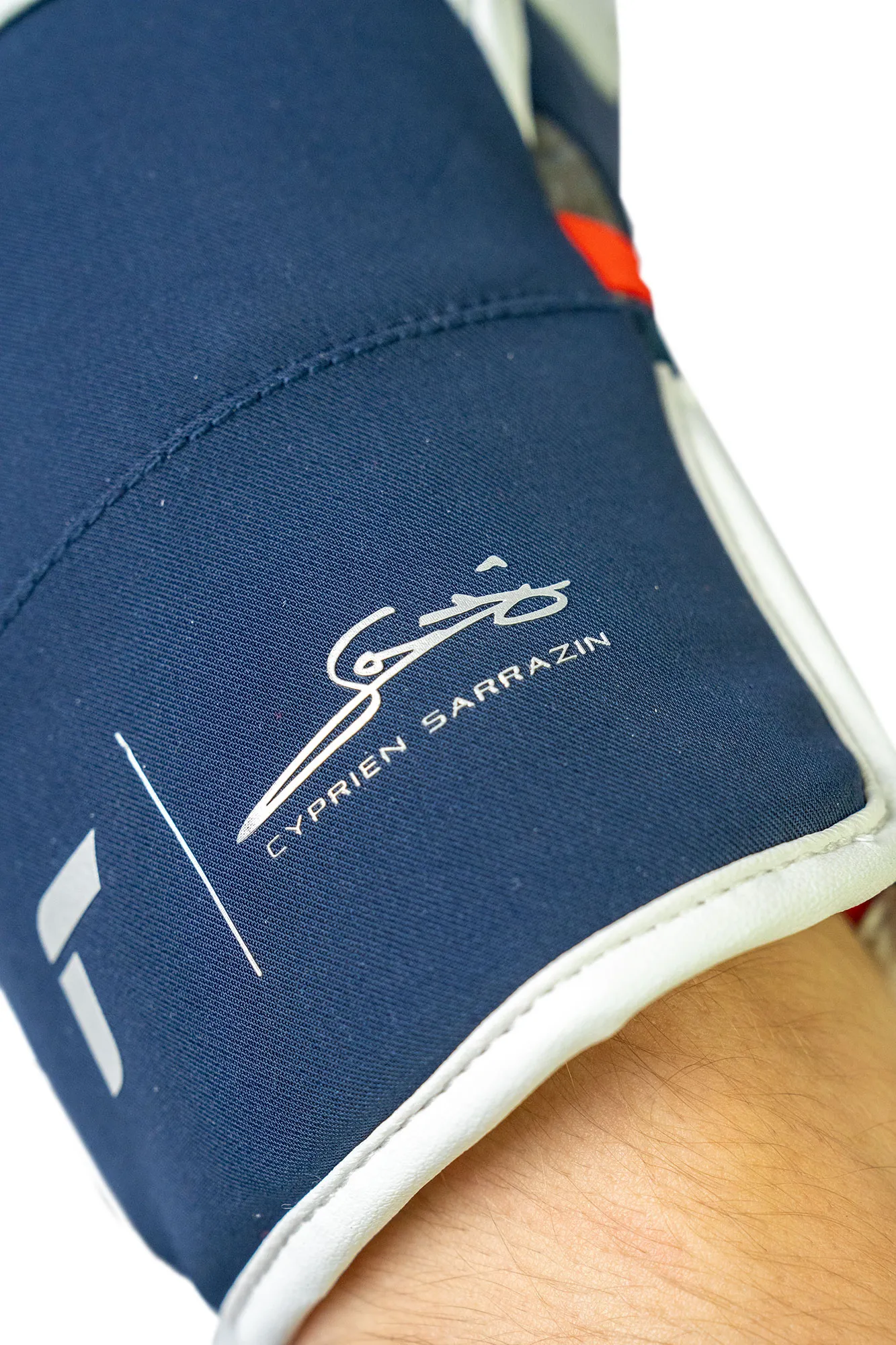 Nahaufnahme einer marineblauen Manschette mit weißem Rand, signiert mit "Cyprien Sarrazin".
