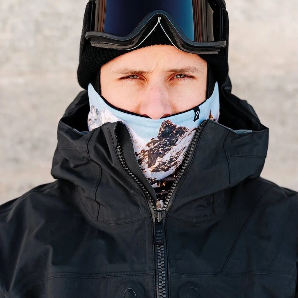 Porträt einer Person mit schwarzer Mütze, Skibrille und "The Mask Black" Neckwarmer mit Bergmotiv unter einer schwarzen Jacke.