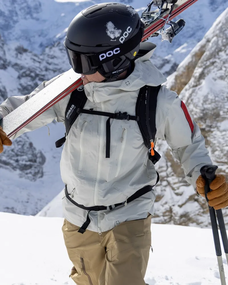 Skifahrer mit Z-2 HD GORE-TEX Pro 3L Shell Jacket in Castle Wall, mit Skiern und Stöcken in verschneiter Berglandschaft.