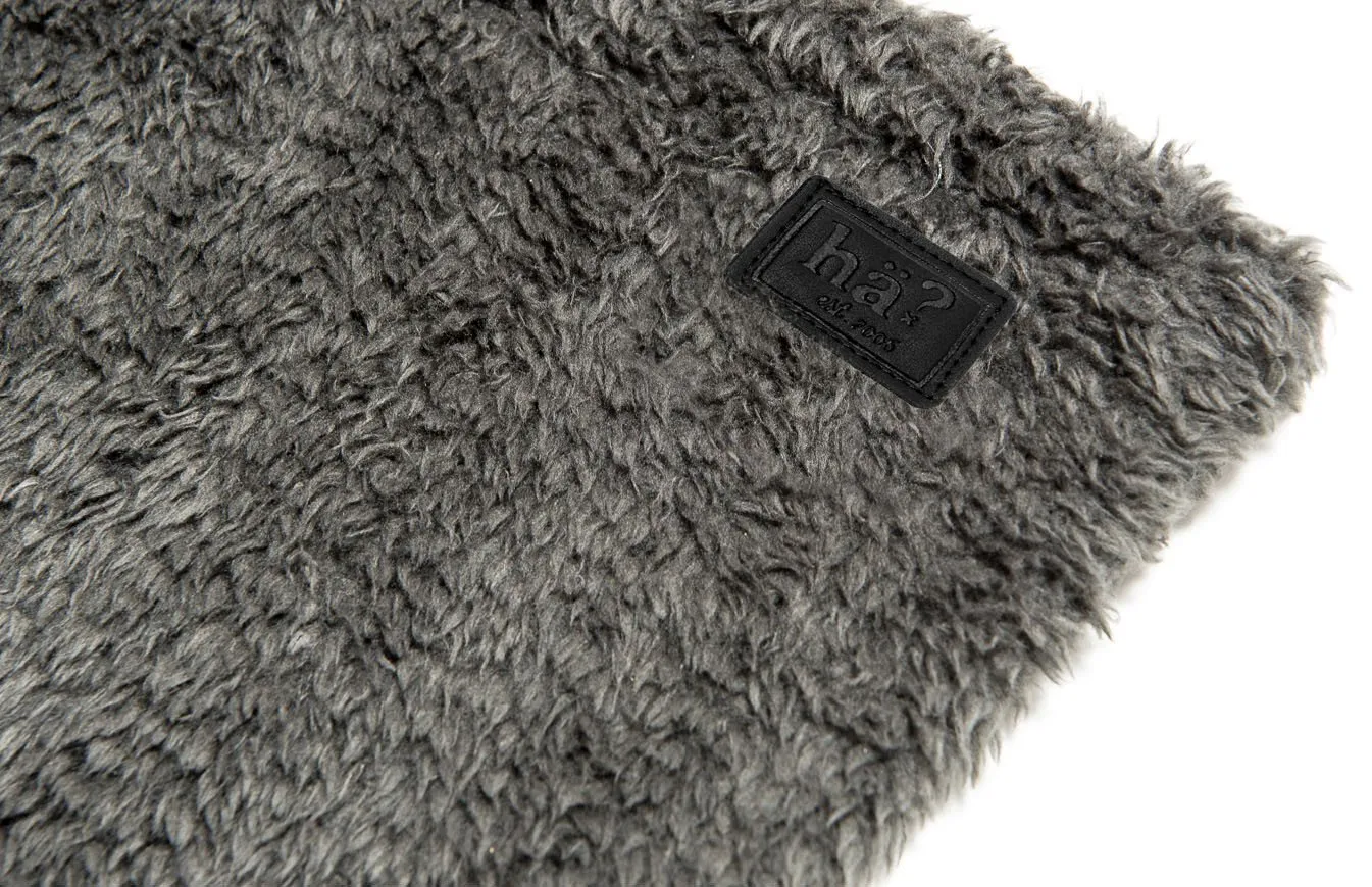 Detailaufnahme eines grauen Wellness Neckwarmers mit flauschigem Polar Fleece und Lederpatch mit Logo.