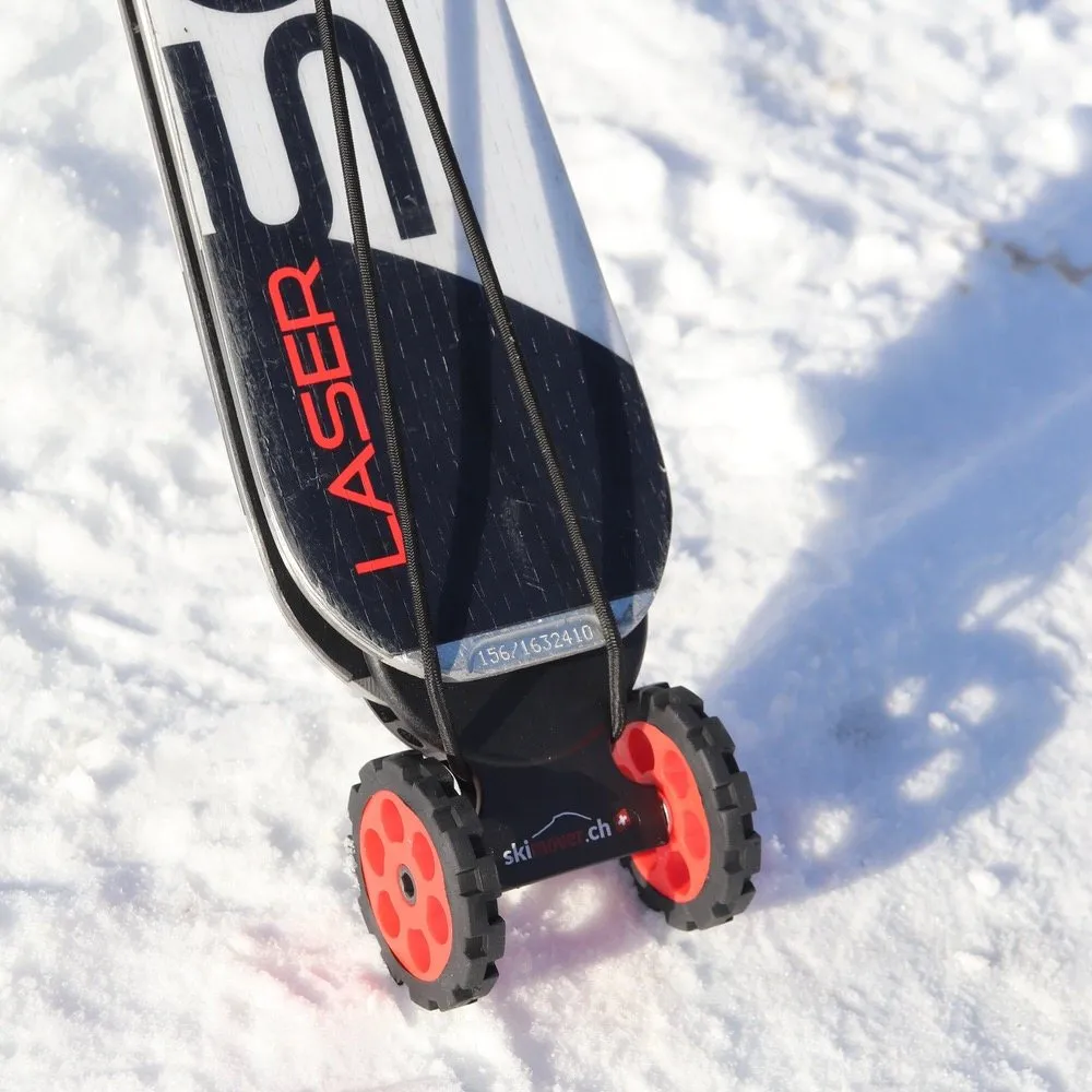 Ski mit montiertem, rotem Skimover Easy auf Schnee. Der Skimover hat zwei Räder. Das Ski-Ende ist schwarz-weiss.