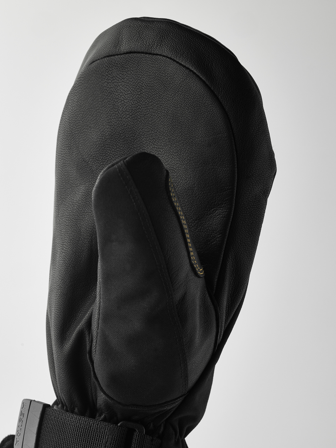 Schwarzer Lederhandschuh Detailaufnahme eines schwarzen Lederhandschuhs mit Daumen, Manschette mit Band und Schnalle vor hellem Hintergrund.