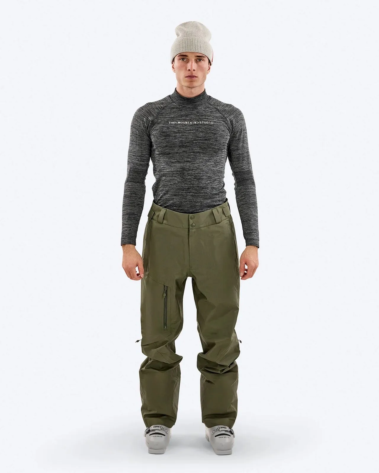 Ein Mann mit Mütze, langärmligem Oberteil und Skihose steht vor einem weißen Hintergrund.