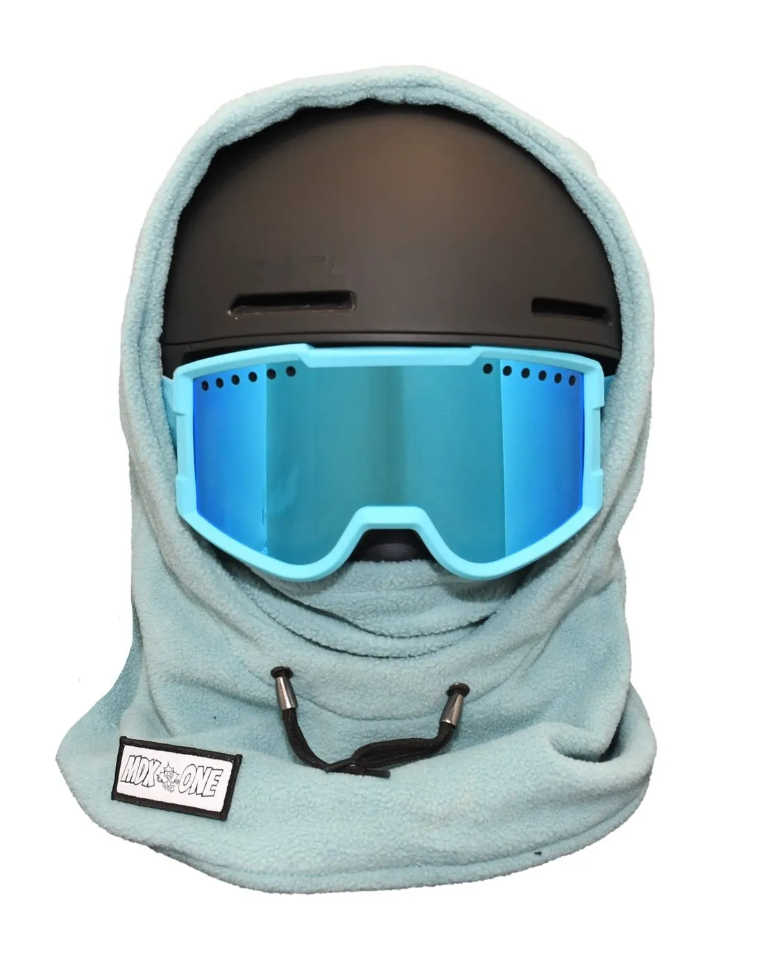 Tealblaue Sturmhaube aus weichem Polar Fleece bedeckt schwarzen Skihelm und reicht über Hals und Gesicht. Blaue Skibrille mit hellblauem Rahmen sitzt darüber. Helmkompatible Balaclava für Kinder, optimaler Kälteschutz. MDX ONE Etikett sichtbar.