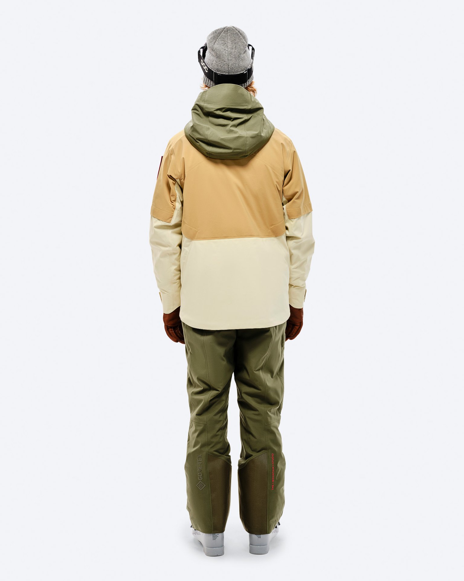 Person von hinten in Winterbekleidung. Gore-Tex P-1 Hose in Winter Moss, beige-braune Jacke mit grüner Kapuze.