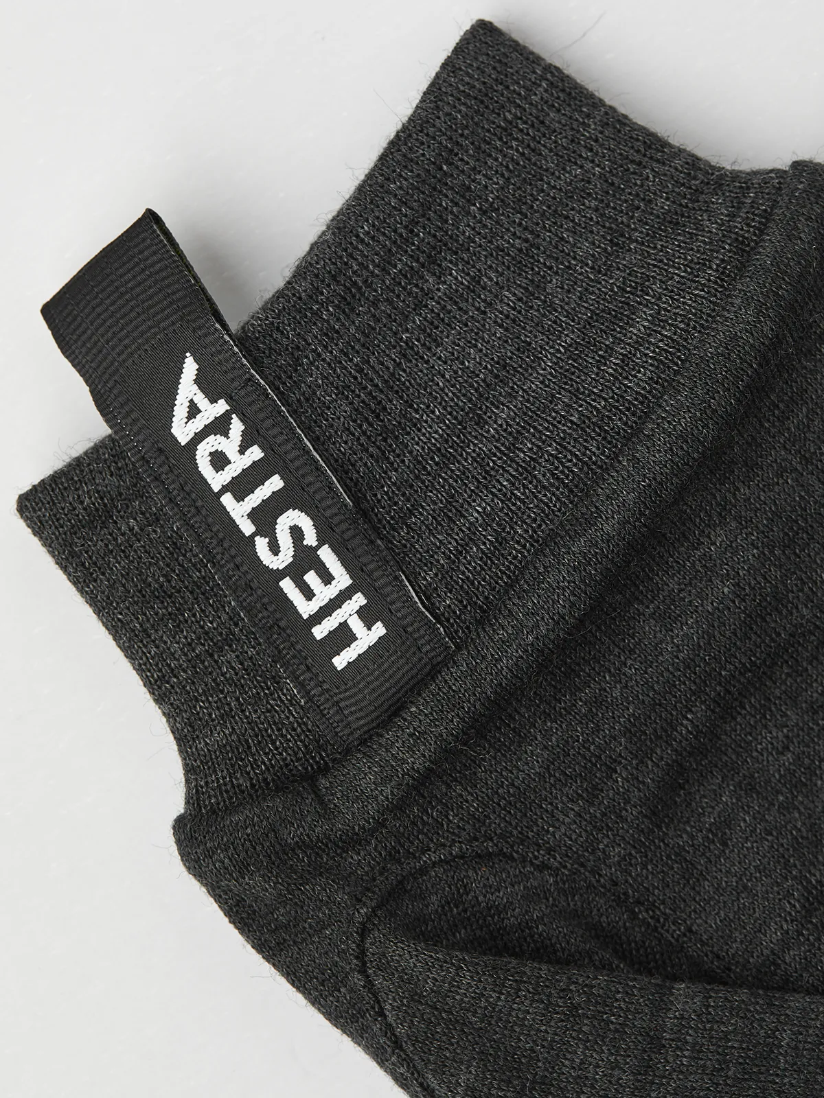 Nahaufnahme eines grauen Merino Wool Liner Active Handschuhs mit dem Hestra-Logo am Bündchen.