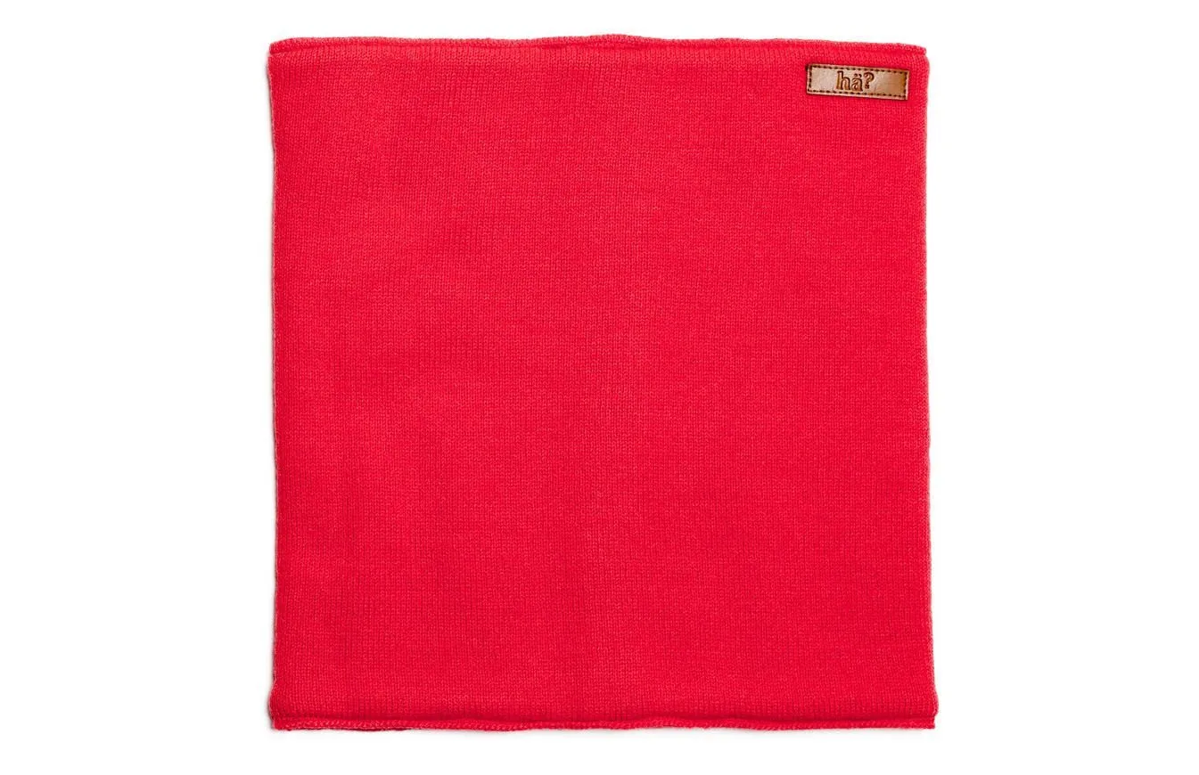 Roter, rechteckiger, gestrickter Neckwarmer mit kleinem Lederpatch in der oberen, rechten Ecke.