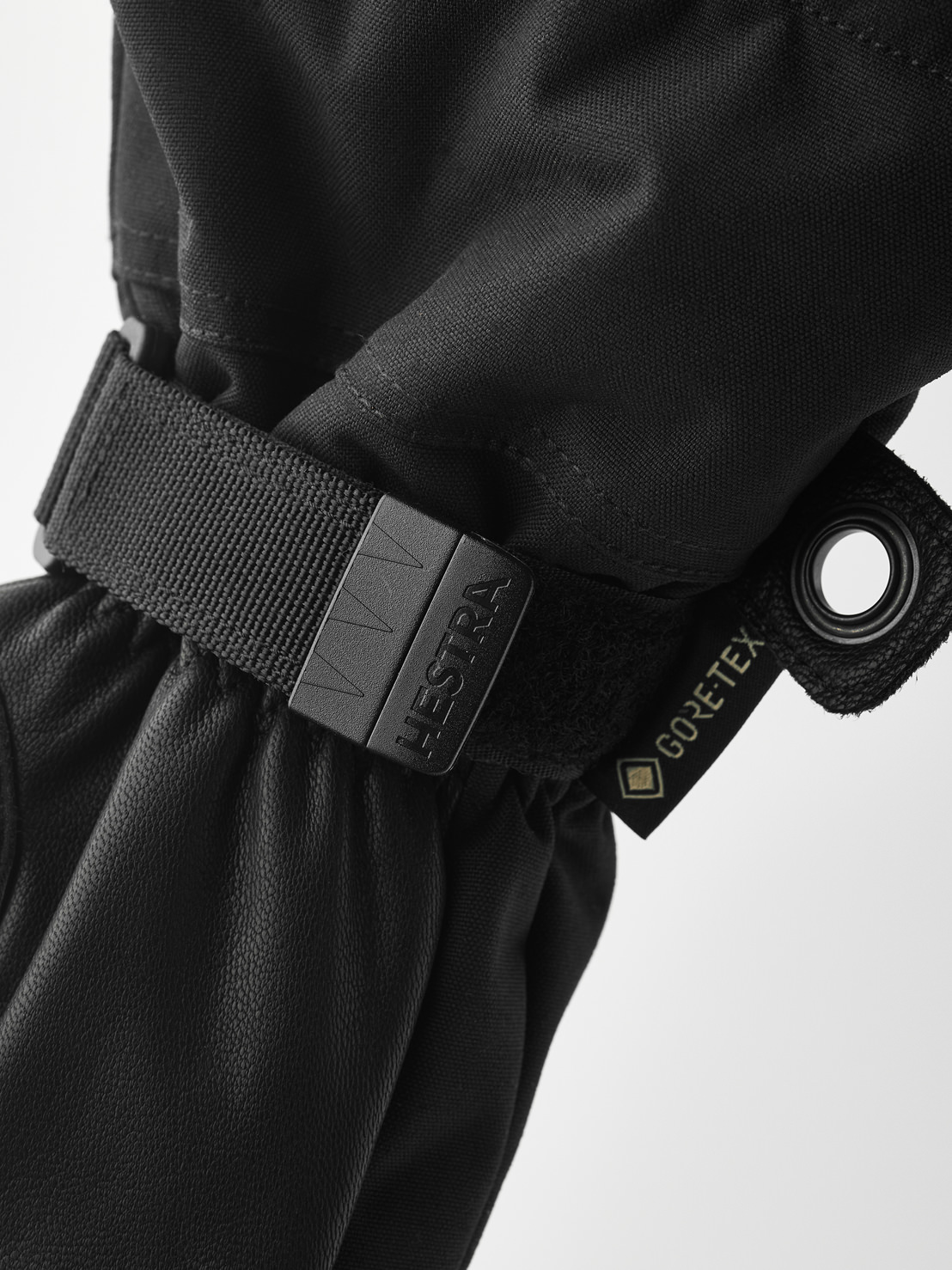 Detailaufnahme eines schwarzen Hestra Army Leather Gore-Tex Fäustlings mit Riemen und Gore-Tex Etikett.

