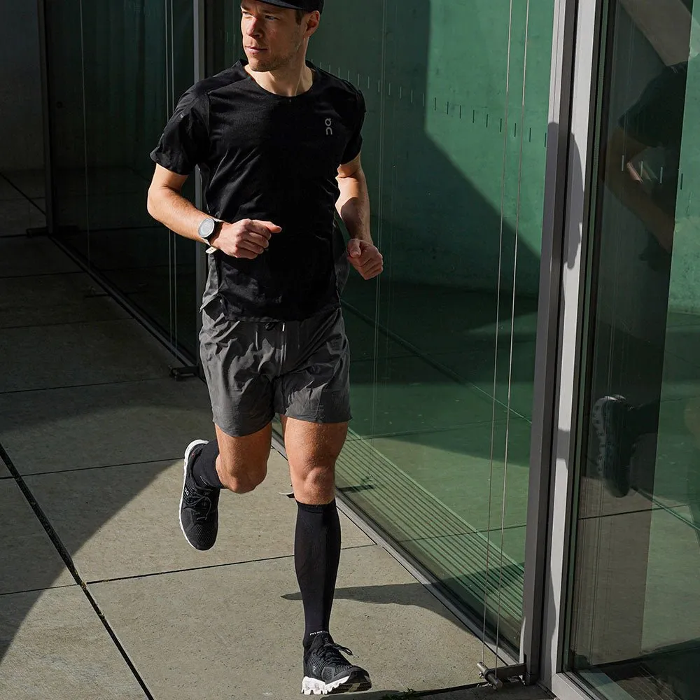 Läufer mit McDavid Elite Recovery Kompressionssocken, schwarzen Laufschuhen, Shorts und T-Shirt beim Laufen.