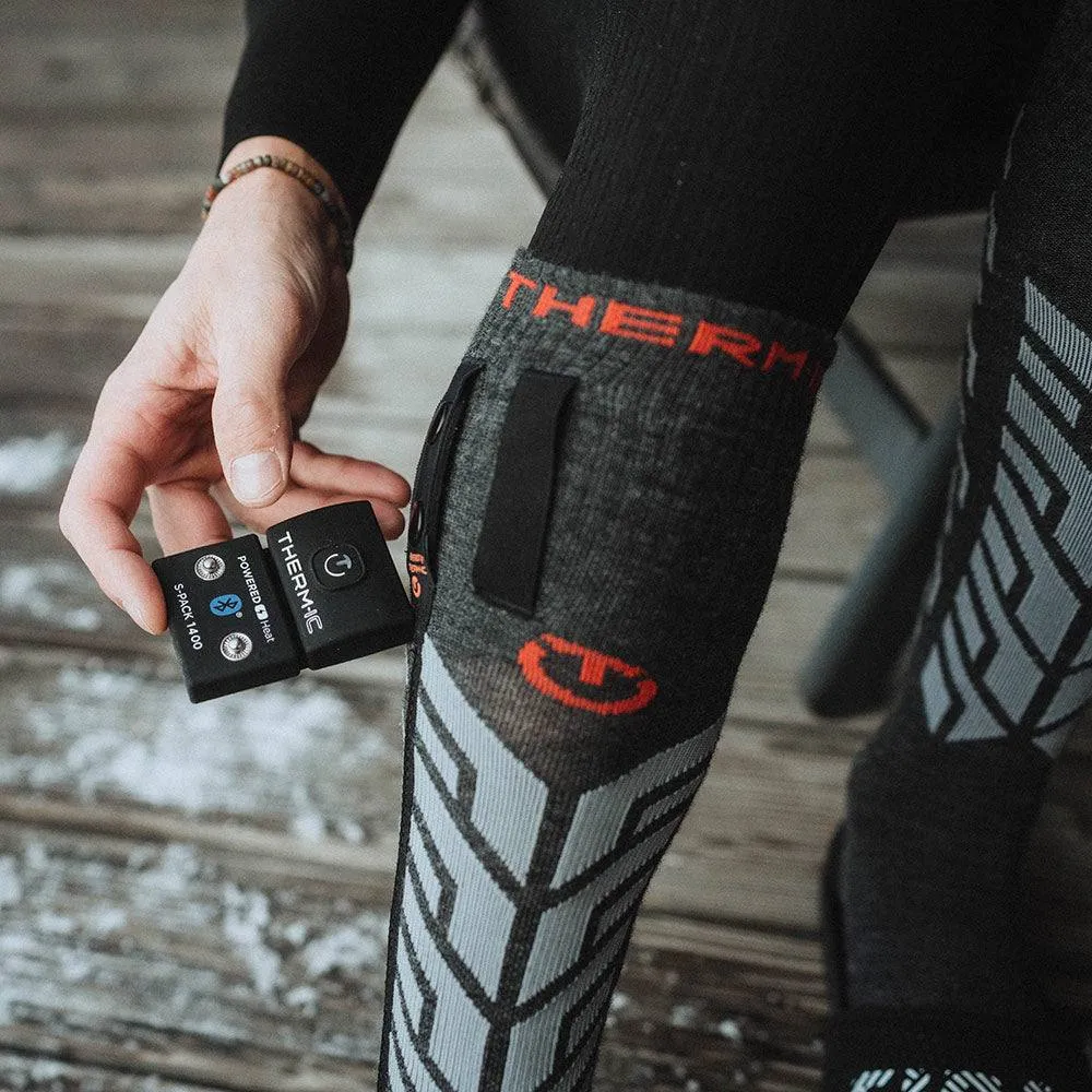 Person zeigt Thermic Ultra Warm Socke mit S-Pack 1400 Batterie in der Hand.