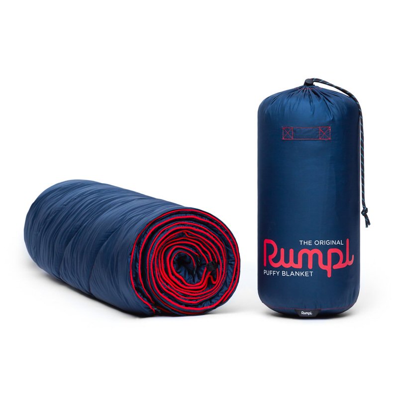 Die Deepwater Rumpl Puffy Blanket, zusammengerollt und in der Tragetasche, vor neutralem Hintergrund.