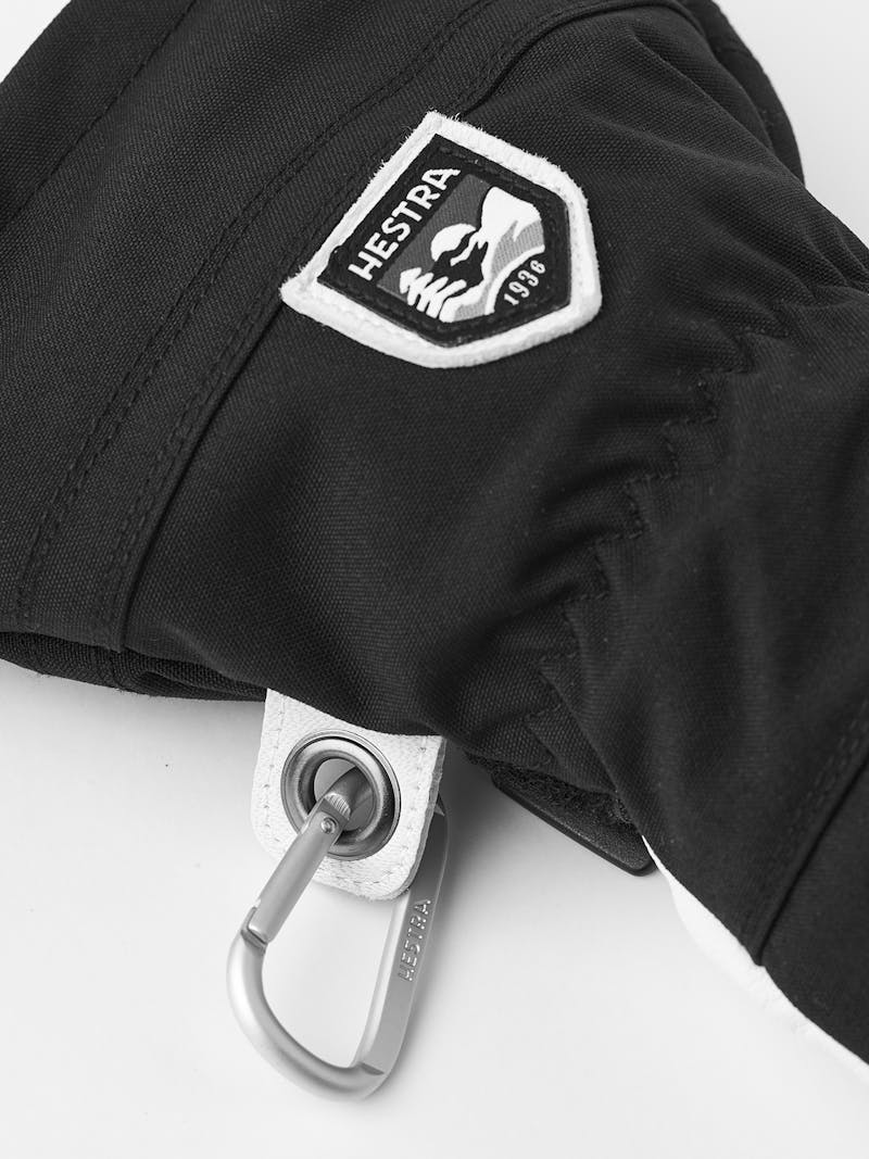 Hestra Army Ski Mitt Detail einer schwarzen Hestra Army Leather Heli Ski Mitt mit Logo und Karabinerhaken.