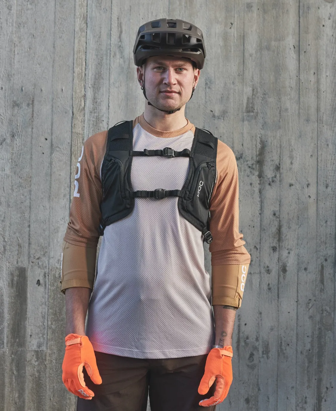 Mann mit Fahrradhelm, orange Handschuhen und Column VPD Backpack. Der Rucksack hat zwei Brustgurte.