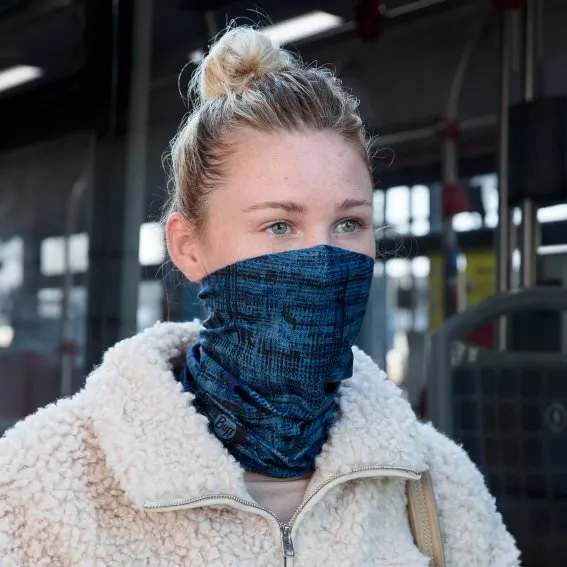 Junge Frau trägt einen blauen Buff Tube Solid als Gesichtsmaske, kombiniert mit einer weißen Teddyjacke.
