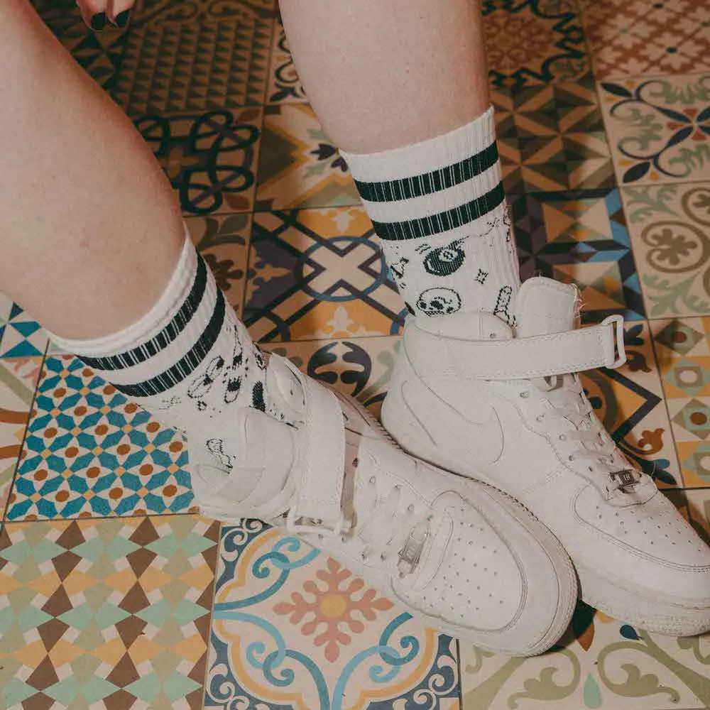 Beine mit "Flash Tattoo - Mid High" Socken und weißen Schuhen auf einem gemusterten Fliesenboden.