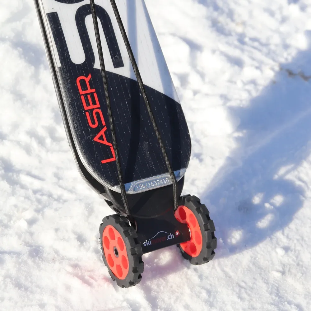 Ski mit montiertem, rotem Skimover Easy auf Schnee. Der Skimover hat zwei Räder. Das Ski-Ende ist schwarz-weiss.
