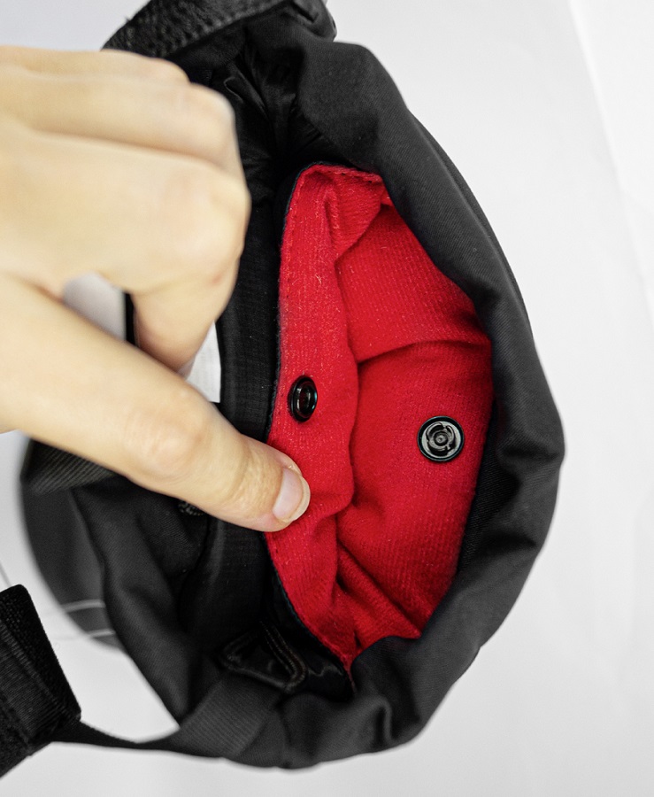 Reusch Volcano Pro GTX Mittens Geöffneter Reusch Volcano Pro GTX Mitten mit rotem Innenfutter, gesichert durch Druckknöpfe. Eine Hand zeigt auf das Futter.