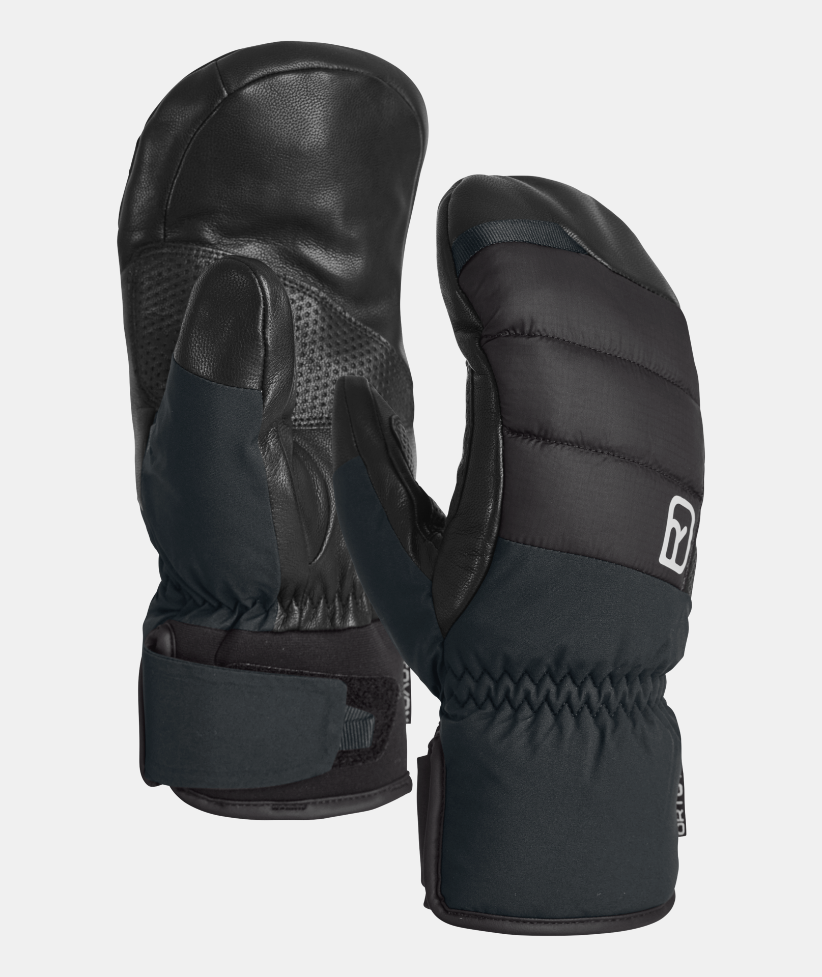 Zwei schwarze Ortovox Freeride Cozy Mitten Fäustlinge vor neutralem Hintergrund. Details aus Leder und Steppnähten.