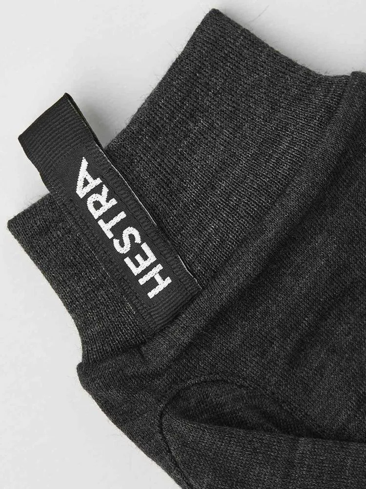 Nahaufnahme eines grauen Merino Wool Liner Active Handschuhs mit dem Hestra-Logo am Bündchen.