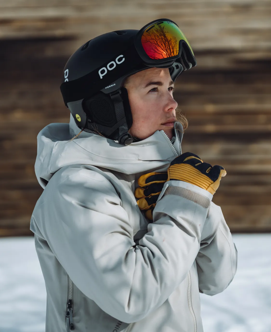 Person mit Poc Fornix Mips Skihelm und Skibrille blickt nach links; reflektierende Bäume in der Brille.