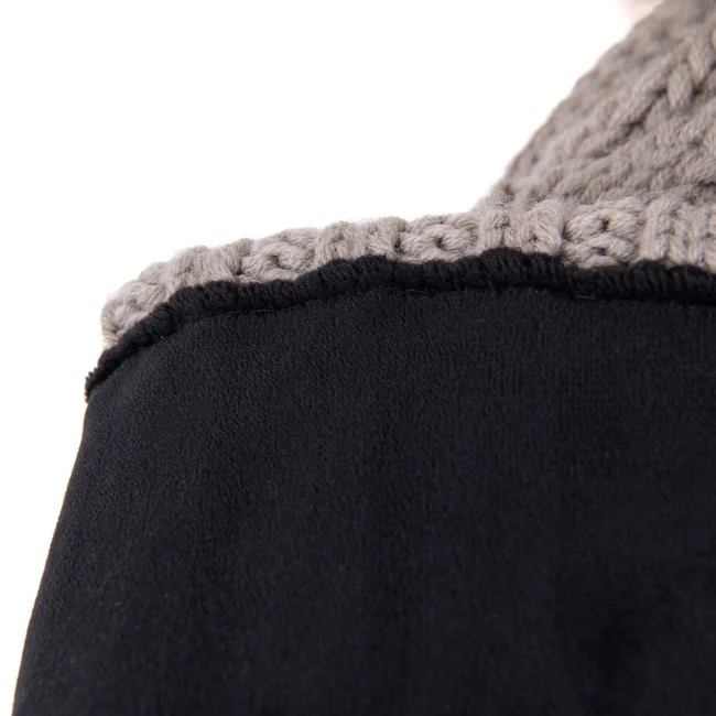 Detailaufnahme von schwarzem Stoff mit einer grauen, gehäkelten Bordüre oben, die eine dekorative Kante bildet.