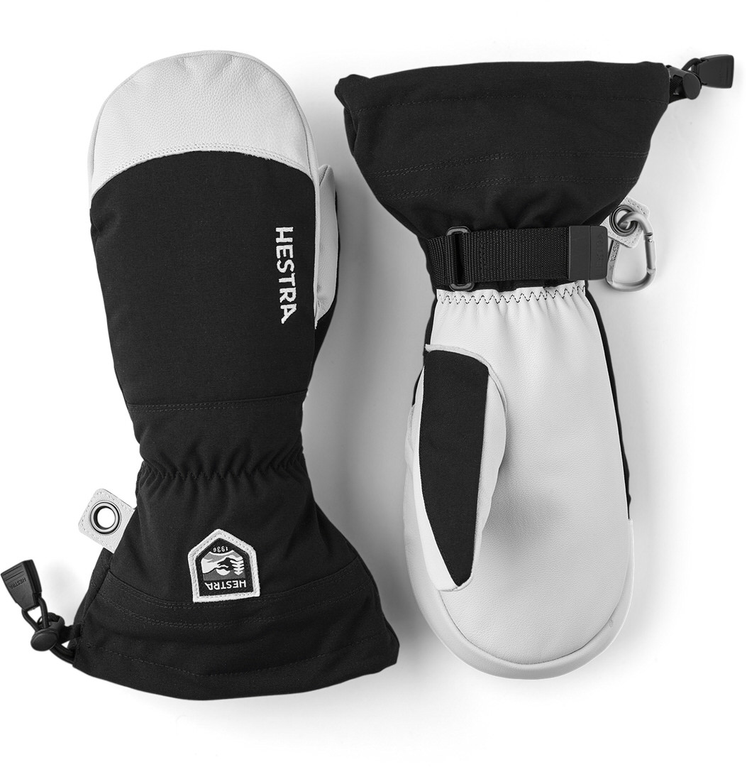 Hestra Ski-Fausthandschuhe Ein Paar schwarze und weiße Hestra Ski-Fausthandschuhe liegen auf weißem Grund.