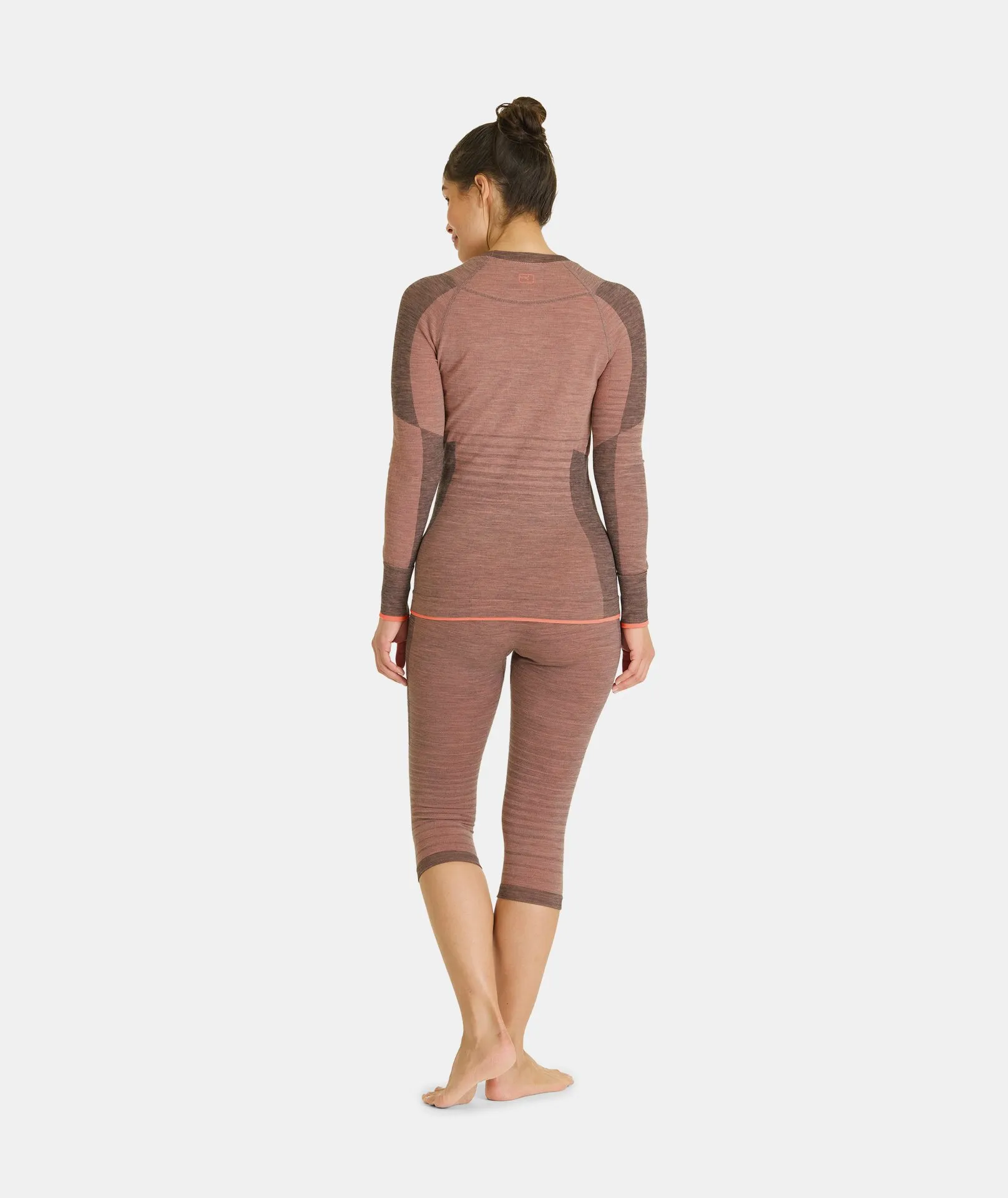 Frau von hinten, trägt bloomfarbene Ortovox 230 COMPETITION SHORT PANTS und ein Langarmshirt.