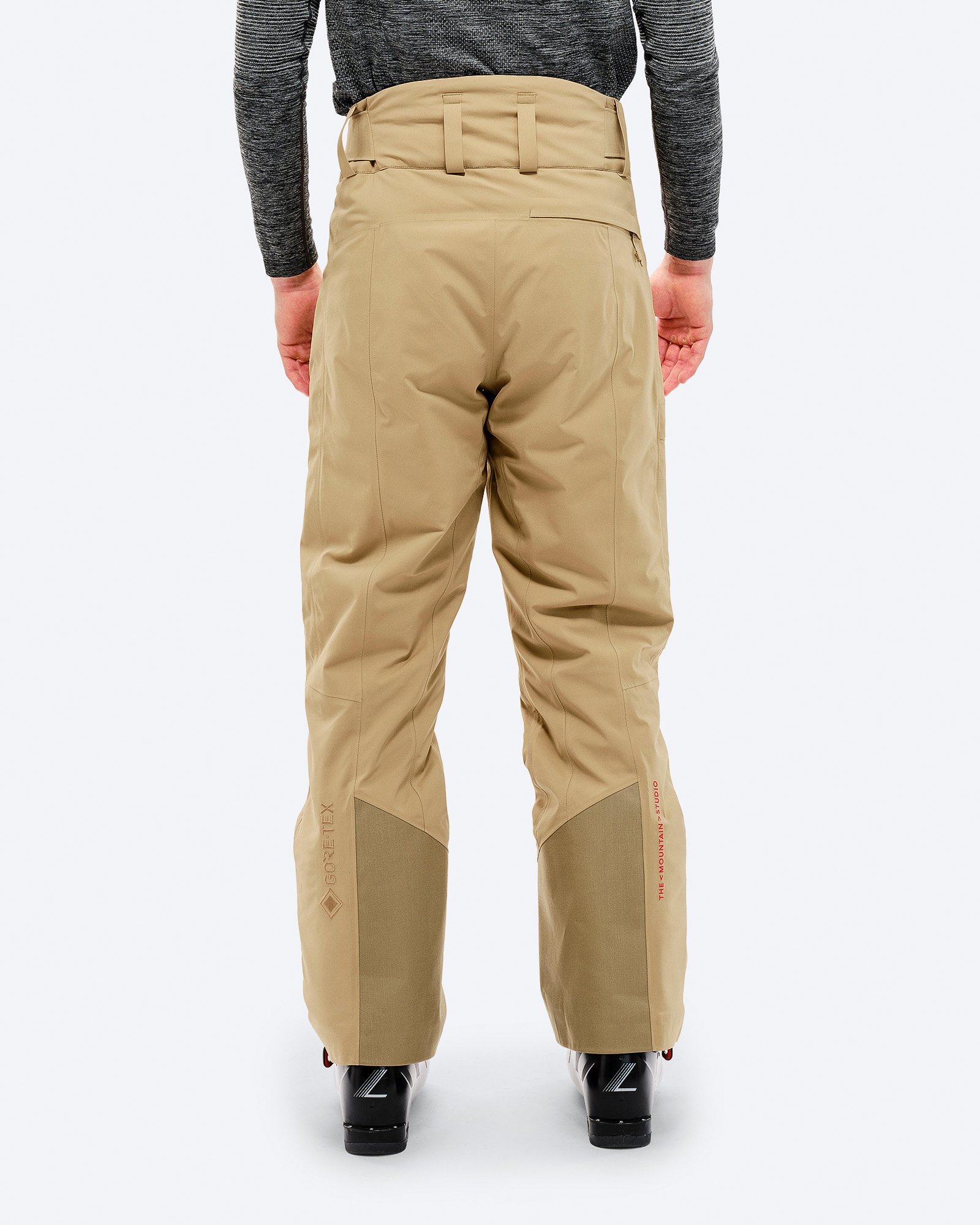 Rückansicht: Person trägt sandfarbene P-1 GORE-TEX 2L Stretch Insulated Pant, Skischuhe.