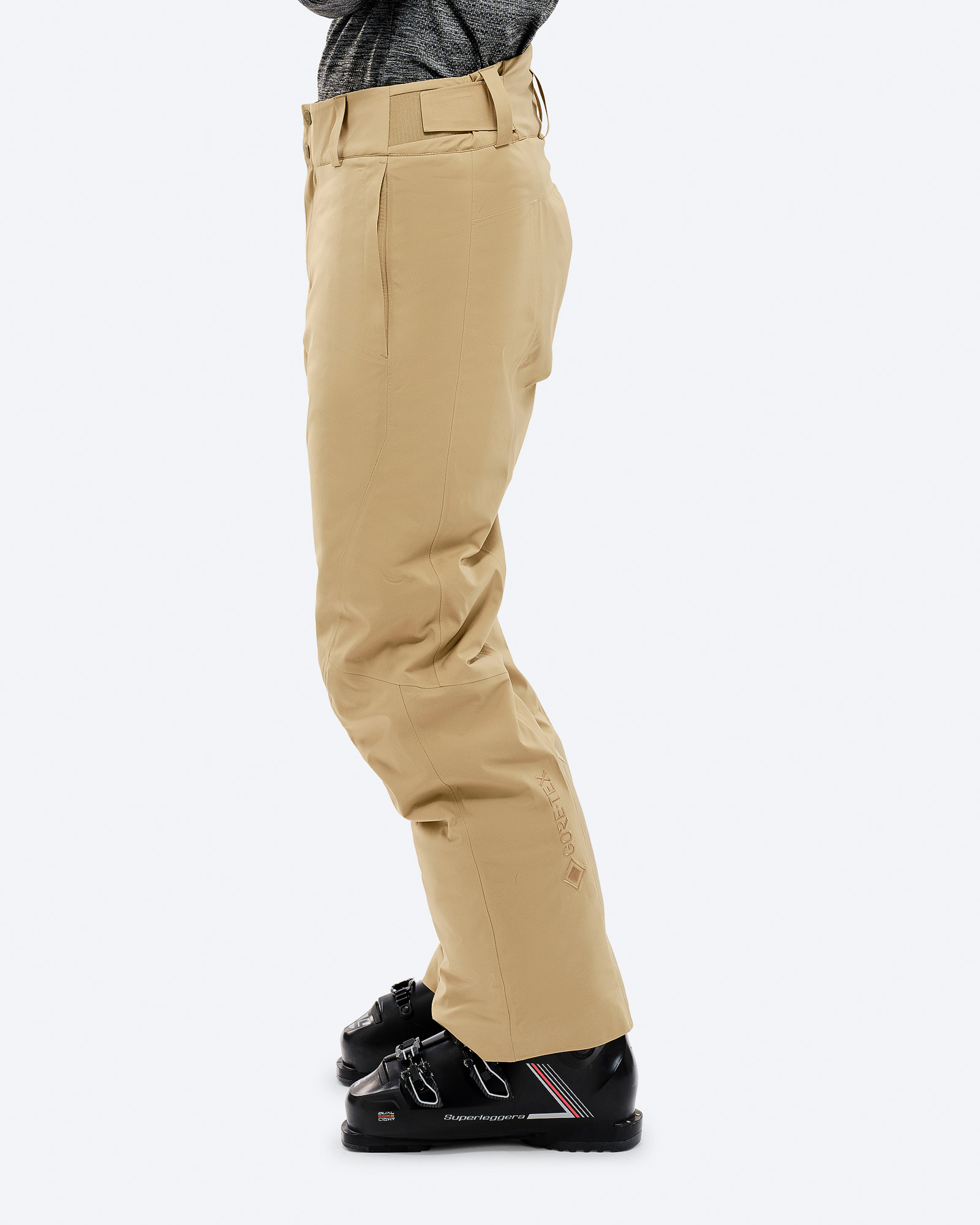 Sandfarbene P-1 GORE-TEX 2L Stretch Insulated Hose in Seitenansicht, getragen mit Skischuhen. Gore-Tex Logo sichtbar.