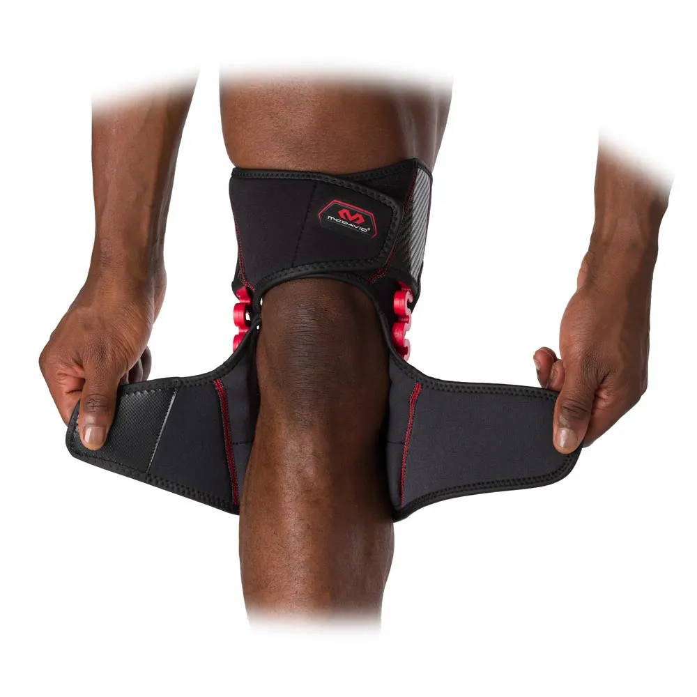 Knie mit McDavid NRG Knee Over Wrap Bandage, die offene Klettverschlüsse in den Händen hält.