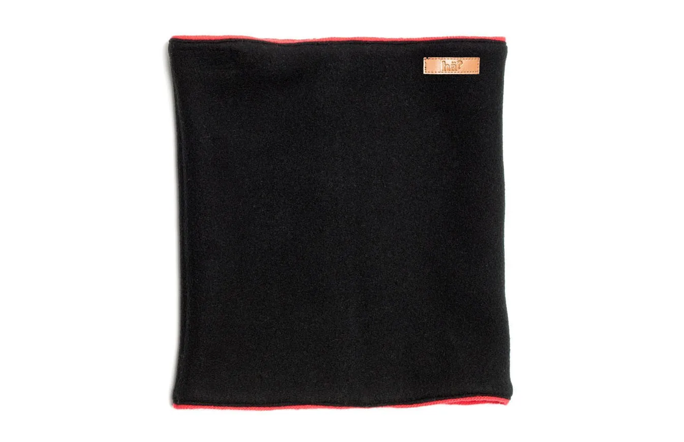 Schwarzer, wendbarer Neckwarmer mit rotem Rand und kleinem, rechteckigen Logo-Patch oben rechts.